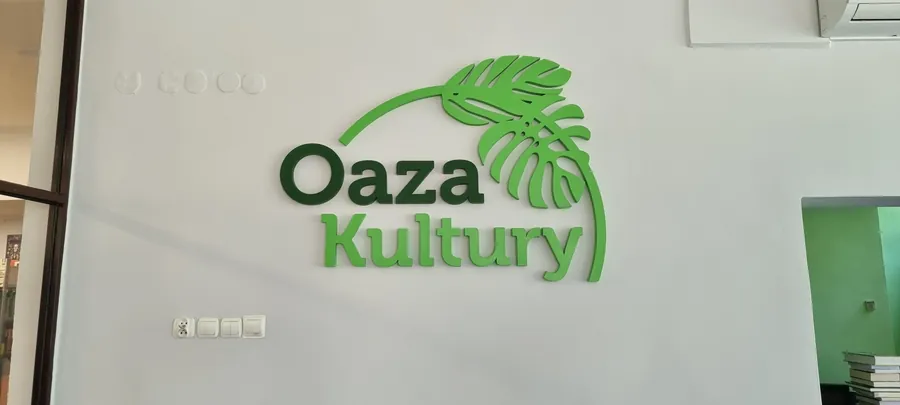 Logotyp przestrzenny z motywem liścia na jasnej ścianie