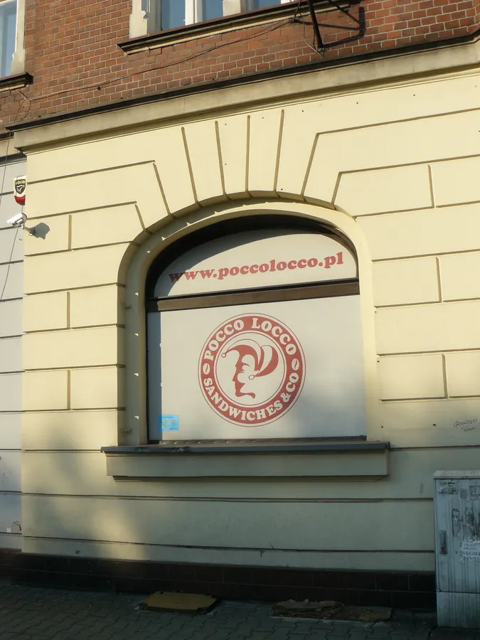 Logotyp na oknie łukowym w kamienicy